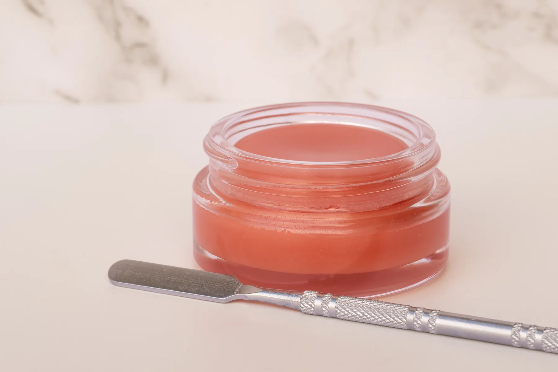An open jar of Pippi and Bloom all over balm beside a steel spatula