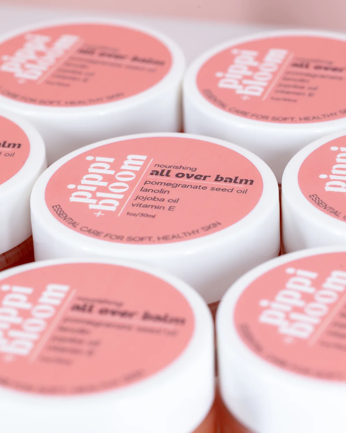 Rows of Pippi and Bloom all over balm lids, the label listing pomegranate seed oil, lanolin, jojoba oil, and vitamin E
