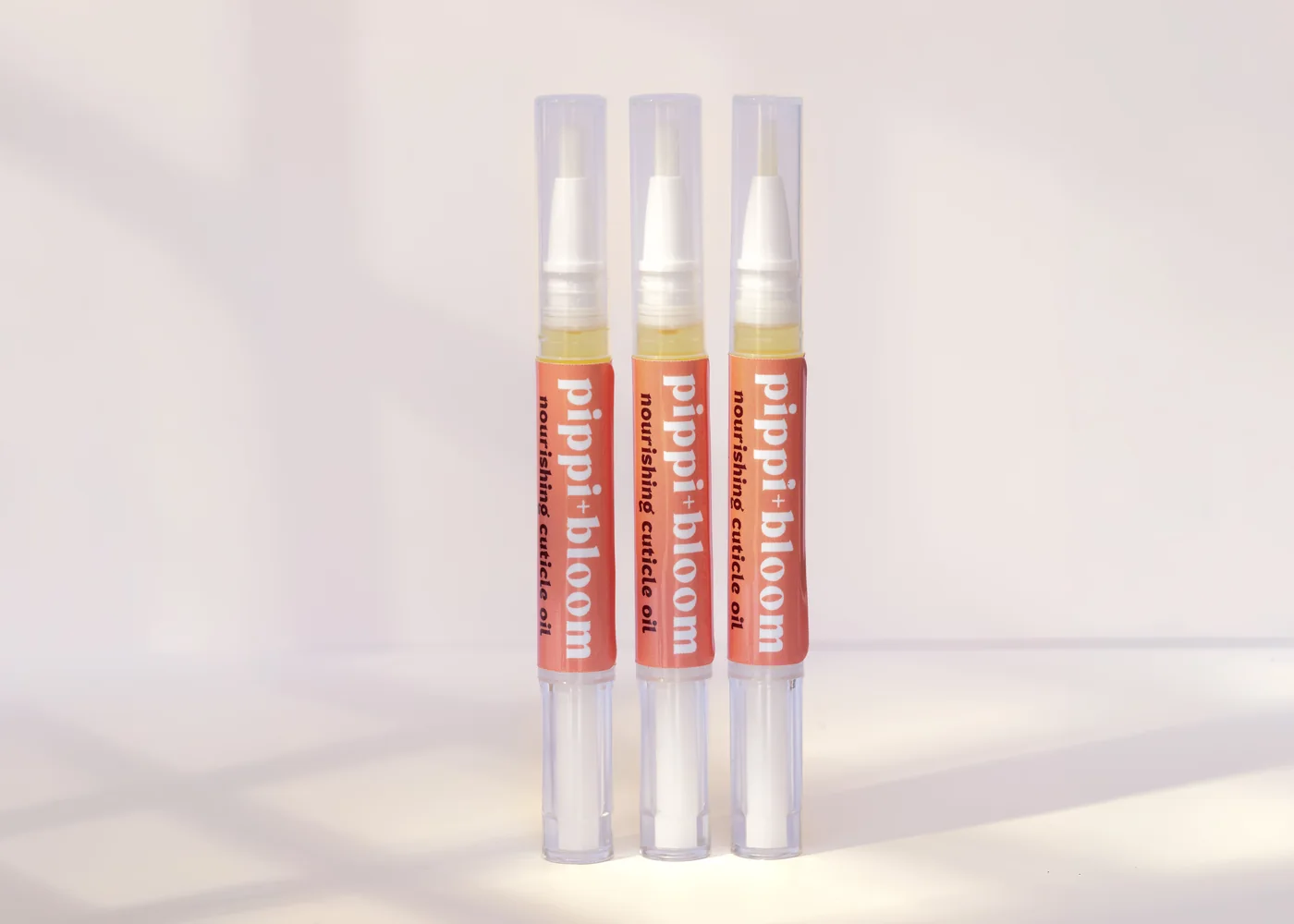Three Pippi and Bloom cuticle oil brush pens standing side by side