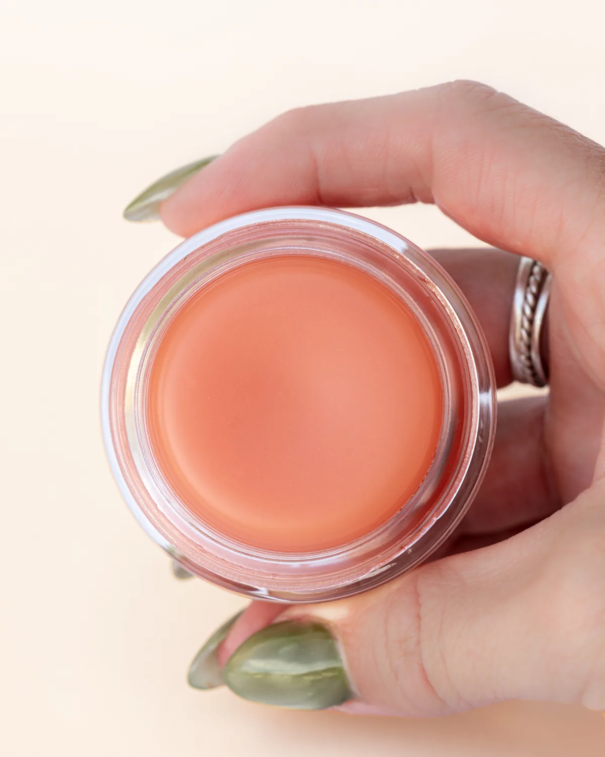 Pippi and Bloom all over balm, the open jar held in one hand to show the balm inside
