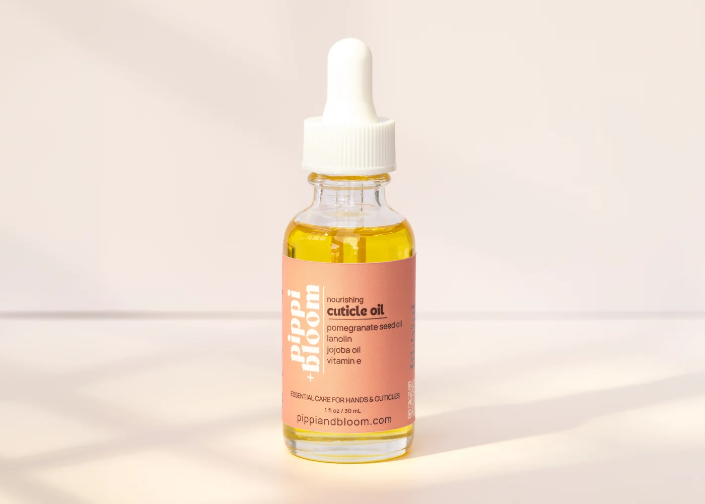 Pippi and Bloom cuticle oil dropper bottle in window light against a pale wall