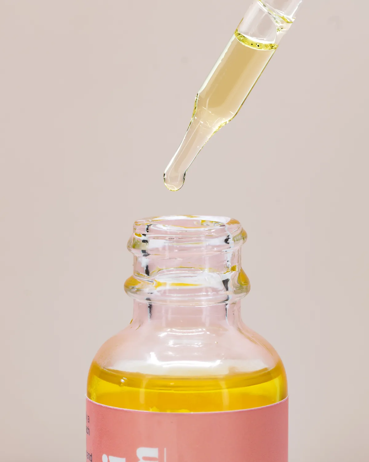 The Pippi and Bloom dropper lifted above the open bottle, a bead of golden oil at its tip
