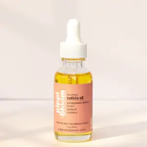 Pippi and Bloom cuticle oil dropper bottle in window light against a pale wall