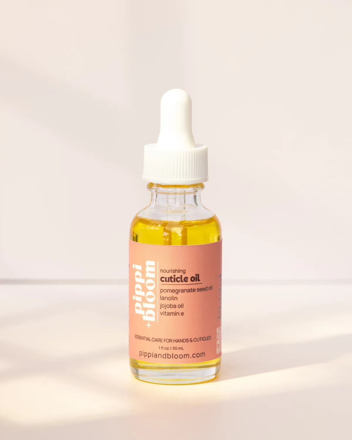Pippi and Bloom cuticle oil dropper bottle in window light against a pale wall