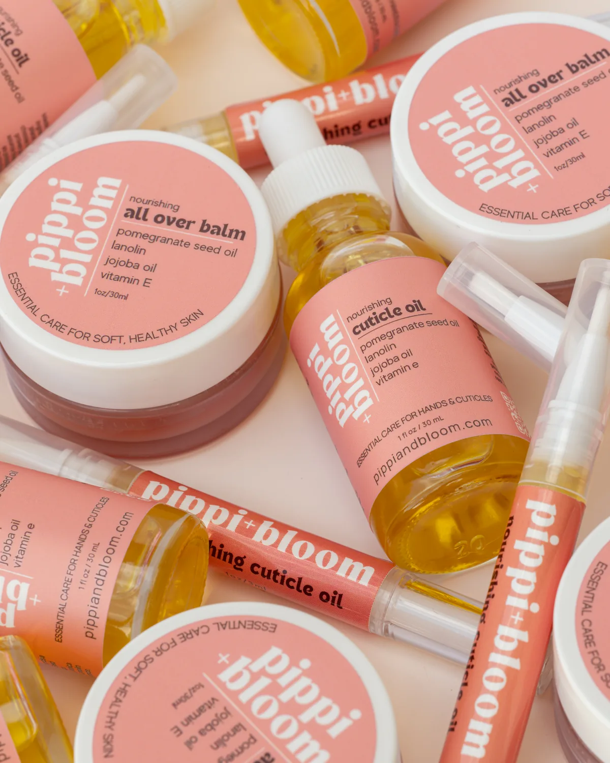 A pile of Pippi and Bloom cuticle oil droppers, brush pens, and all over balm jars