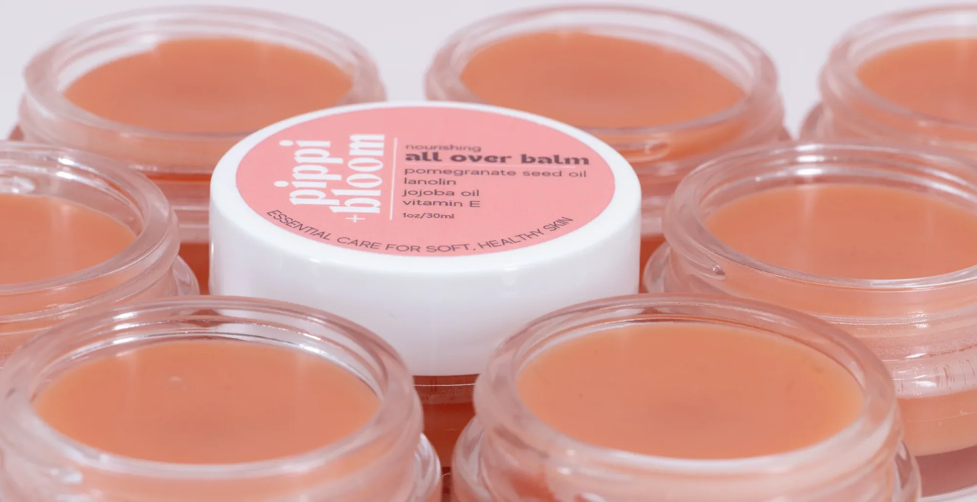 Open jars of Pippi and Bloom all over balm gathered around one lidded jar
